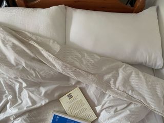 Pillows on a bed with books on top of the duvet