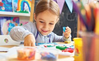 Smiling 5 year old girl works with colorful clay