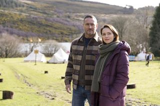 Kara Tointon and Will Mellor as Dani Oxley and Jimmy Spencer in The Teacher. They are at an outdoor adventure centre with hills in the background - she is wearing a padded coat and he has a thick shirt-jacket on. Both are looking at something just to the left of the camera.