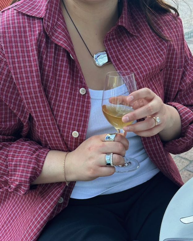 Marina wears a red plaid shirt, white tank top, black pants.