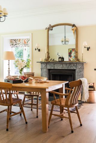 wooden dining table and chairs in cream dining room with fireplace and mirror
