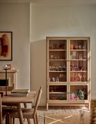 A glass-fronted dresser full of colorful glassware