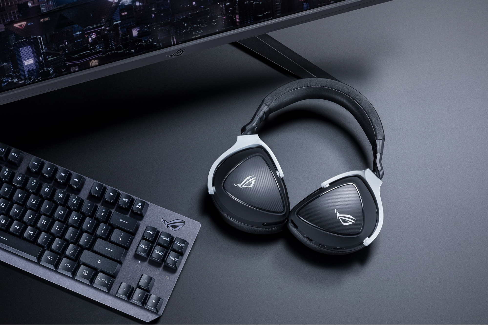 ASUS ROG Delta S Wireless gaming headphones next to a keyboard and monitor
