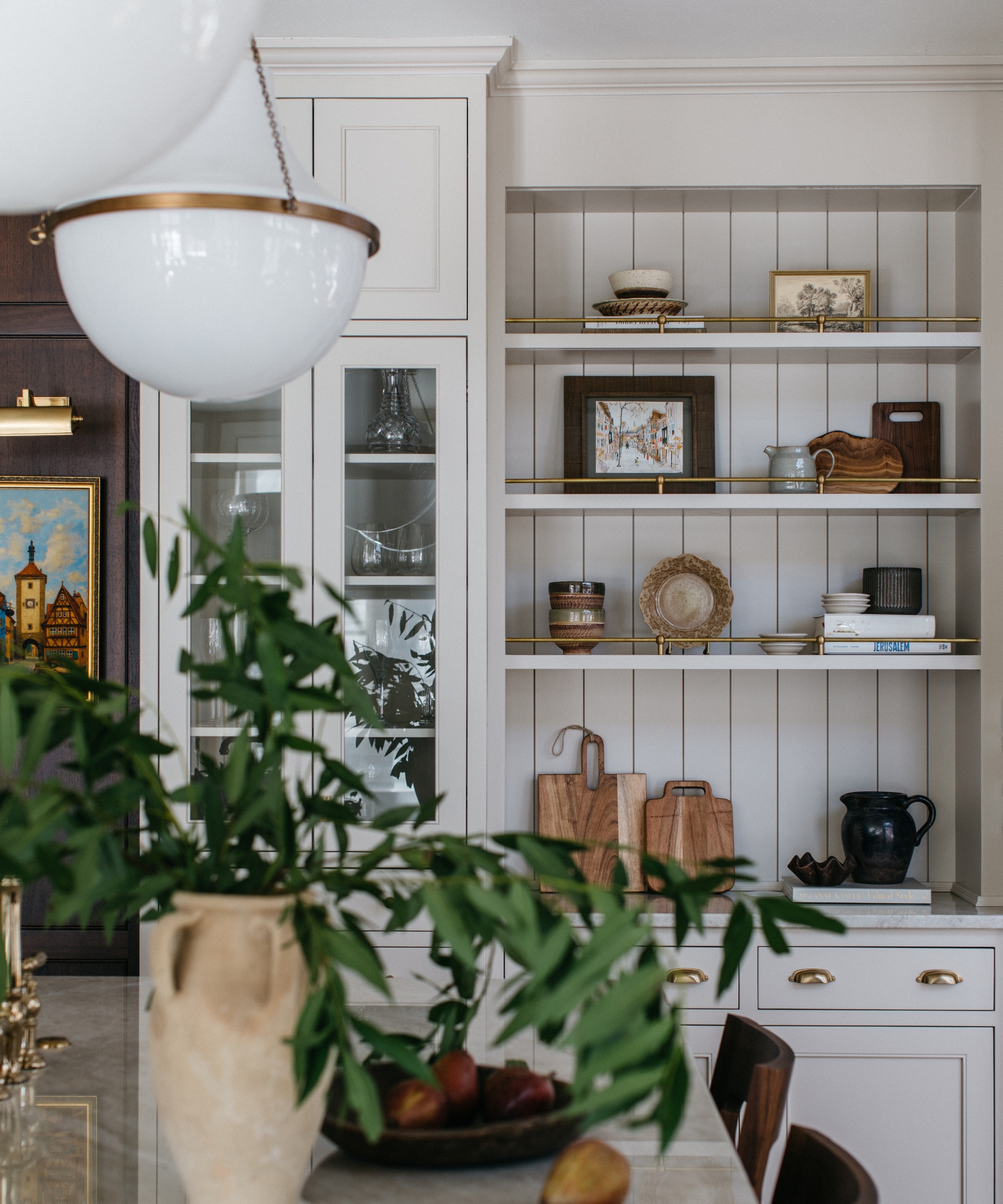 A white kitchen with open shelving filled with art and collected decor