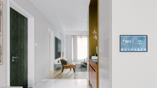 A white living space with a digital thermostat on the wall to highlight tips to save energy in the home