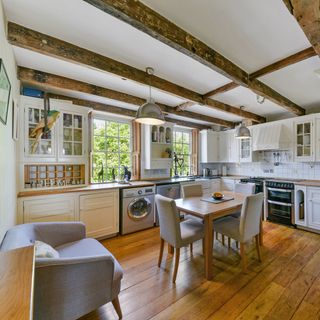 kitchen with white wall white cabinets dinning table and chairs wooden beams on ceiling