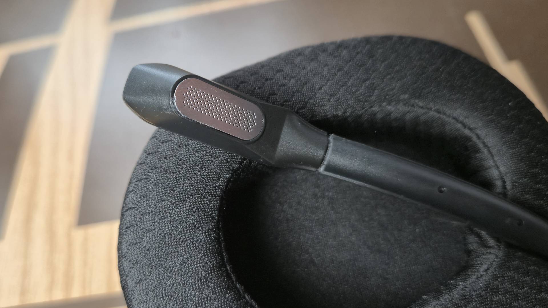 Photo of a close up of a headset microphone. The microphone is sitting on the inner ear cup of the headset.