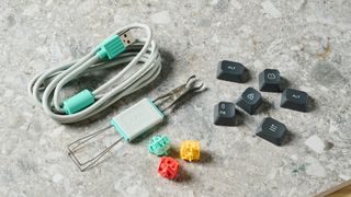 A photo of the NuPhy Halo75 V2's accessories kit, comprising a USB-C cable, a keycap and switch puller, spare keycaps and a spare yellow switch