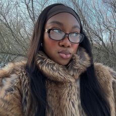 Woman with long hair wearing glasses and a brown fur coat