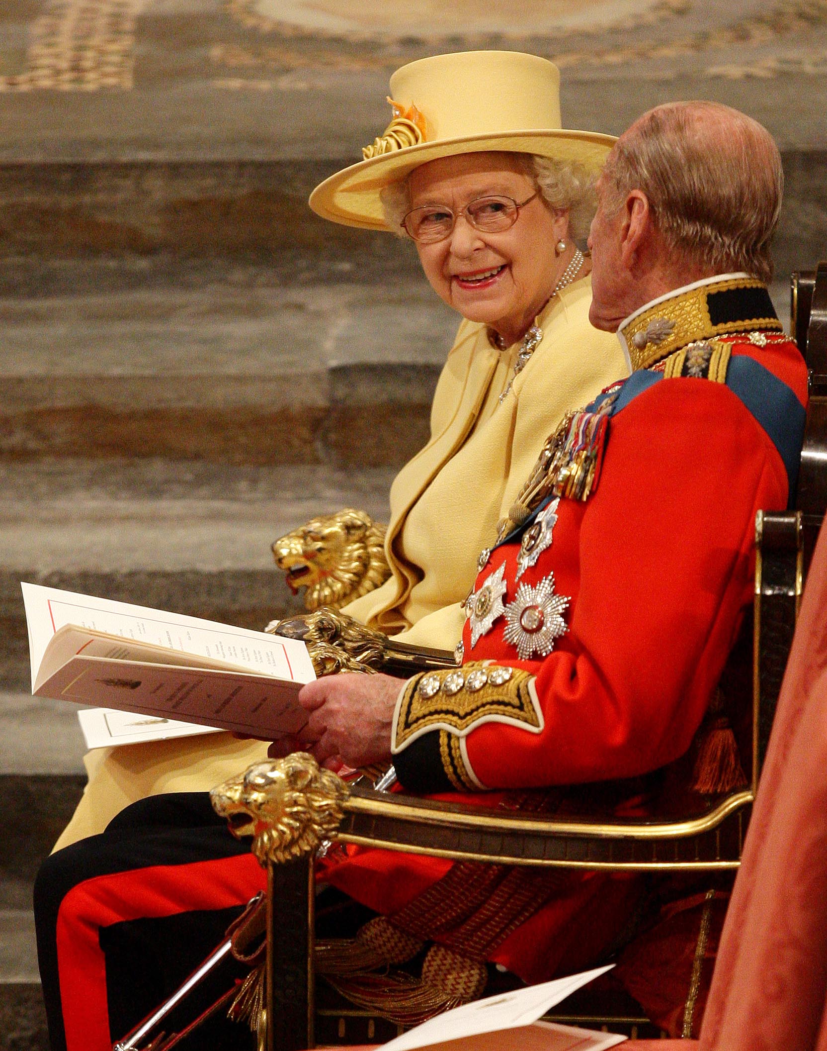 Queen Elizabeth wearing a yellow hat and coat and Prince Philip wearing a red uniform at Prince William and Kate's 2011 wedding
