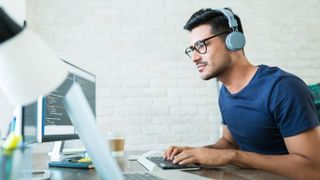 Ein Mann mit Kopfhörern, der einen Laptop benutzt.