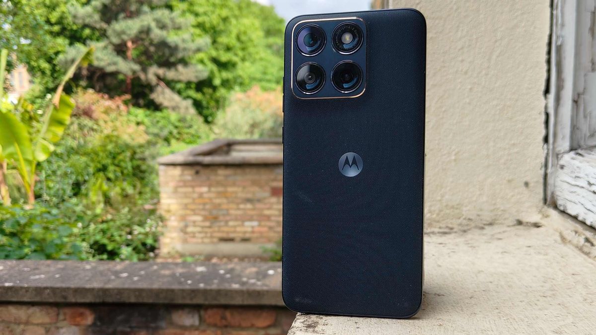 The Motorola Edge 70 Fusion on a window sill, before some bushes.