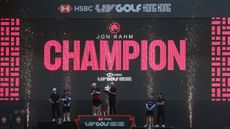 A wide shot of the podium at LIV Golf Hong Kong 2026 with Jon Rahm holding the trophy and Thomas Pieters in third and Thomas Detry in second