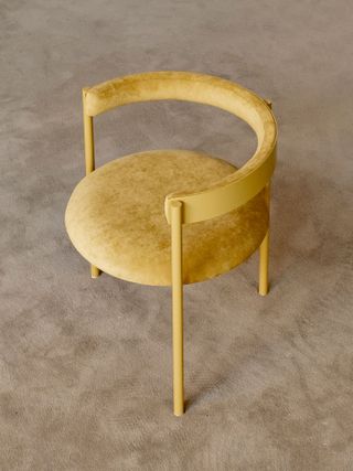 Round shaped yellow chair with velvet seat photographed on a beige carpet