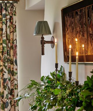 christmas mantel with green foliage and tall taper candles