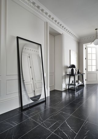 black and white hallway with black marble style tiles, black mirror and console