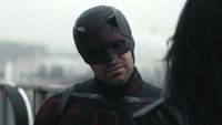 Daredevil in his black and red suit in Season 2 of Born Again, speaking on a rooftop to Jessica Jones during the day.