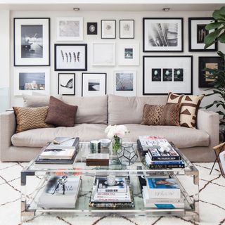White living room with gallery wall, beige sofa and coffee table covered in books