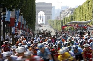 The peloton flies down the Champs Élysées with the Arc de Triomphe behind.
