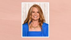 Image of Patsy Palmer smiling with curled ginger hair and wearing a vibrant blue square-neck top and blazer, on a peachy background