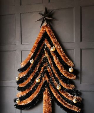 Orange and black tinsel tree with baubles