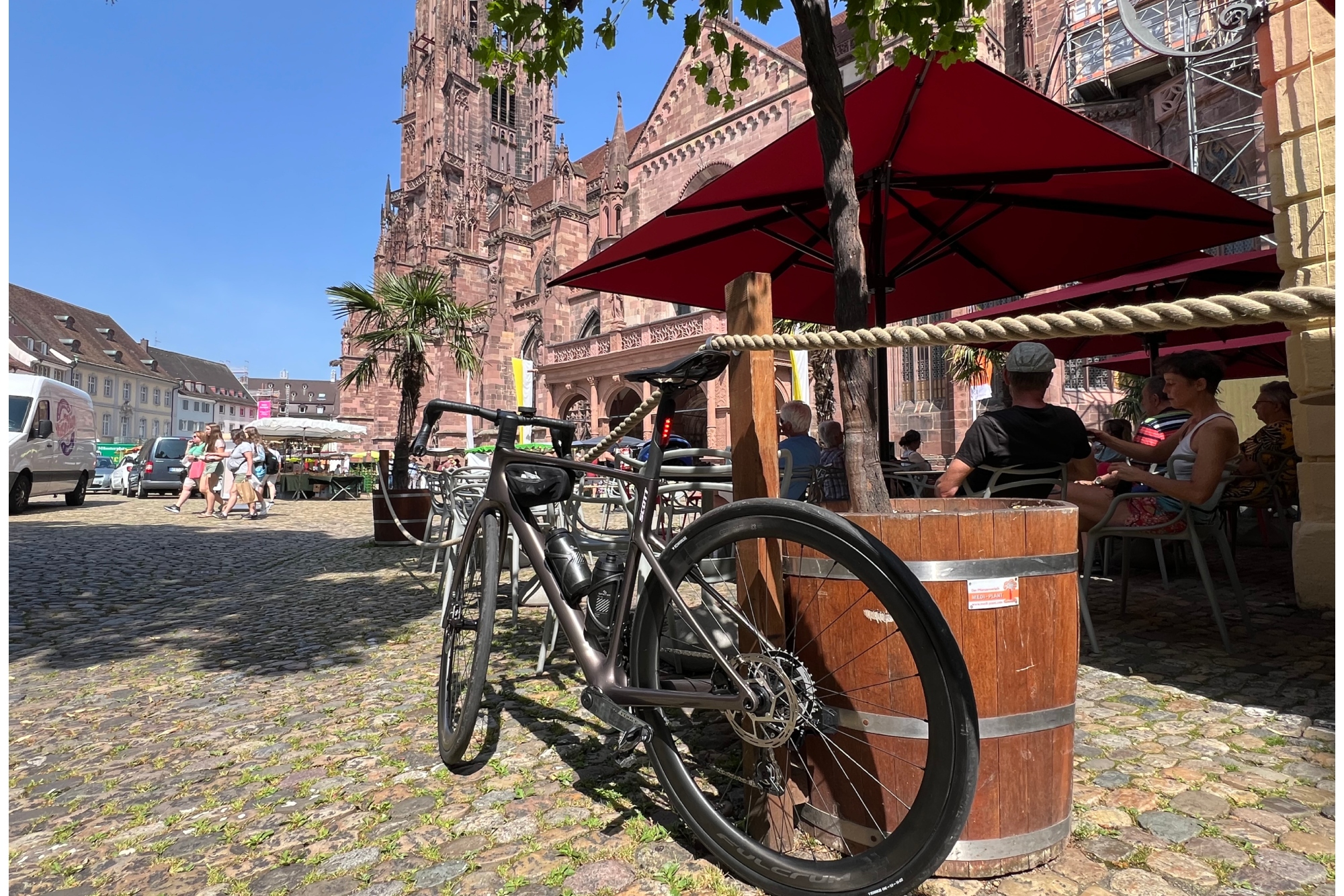 The Scott Addict 10 leaning up against a planter in a town with a church in the background, blue sky and cobbled surface