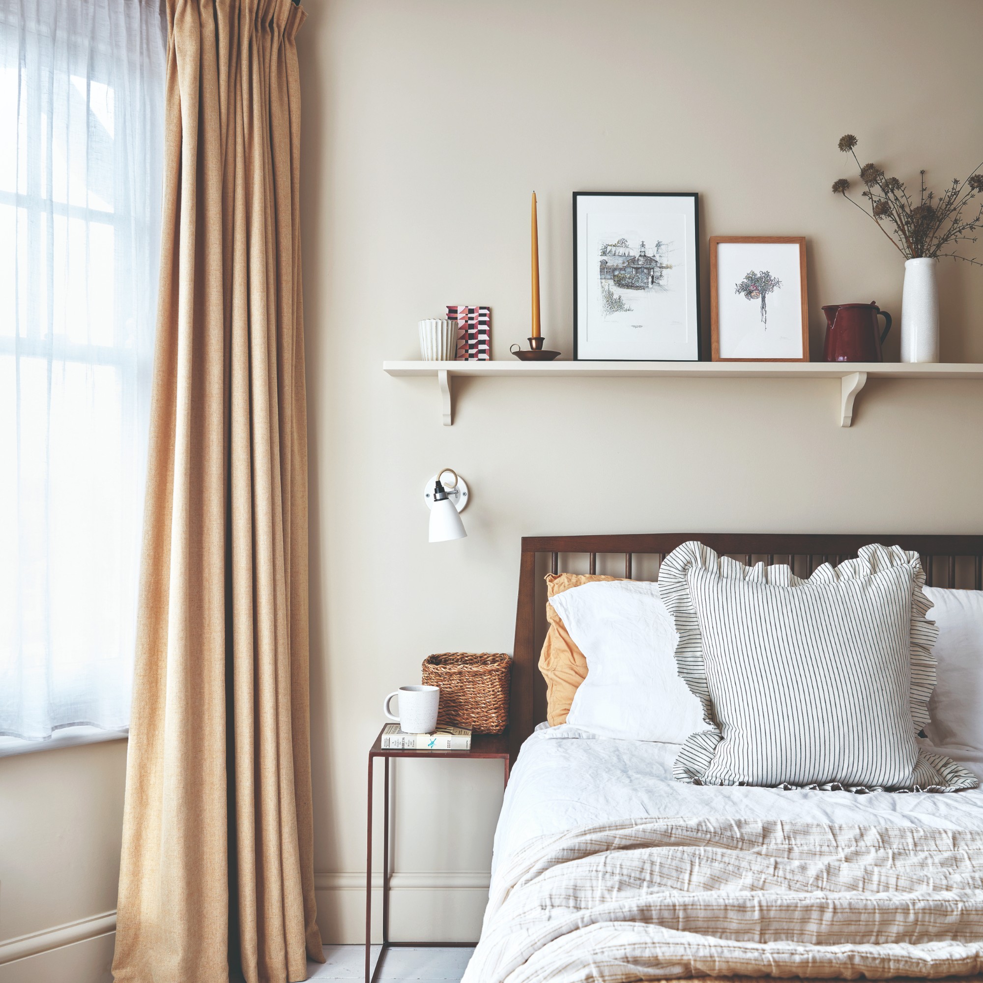 A bedroom painted in off-white with a shelf above the dark wood bed