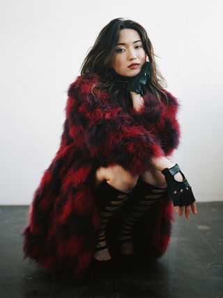 Reina Hardesty wears a fluffy red coat with fingerless leather gloves.