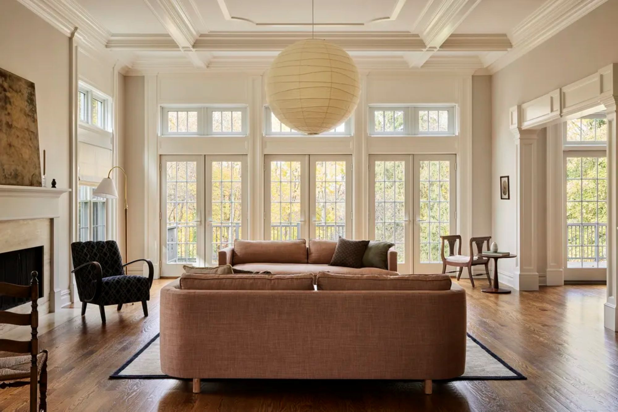 living room with two couches facing each other, a large paper ceiling light, and a wall of windows and doors with no curtains