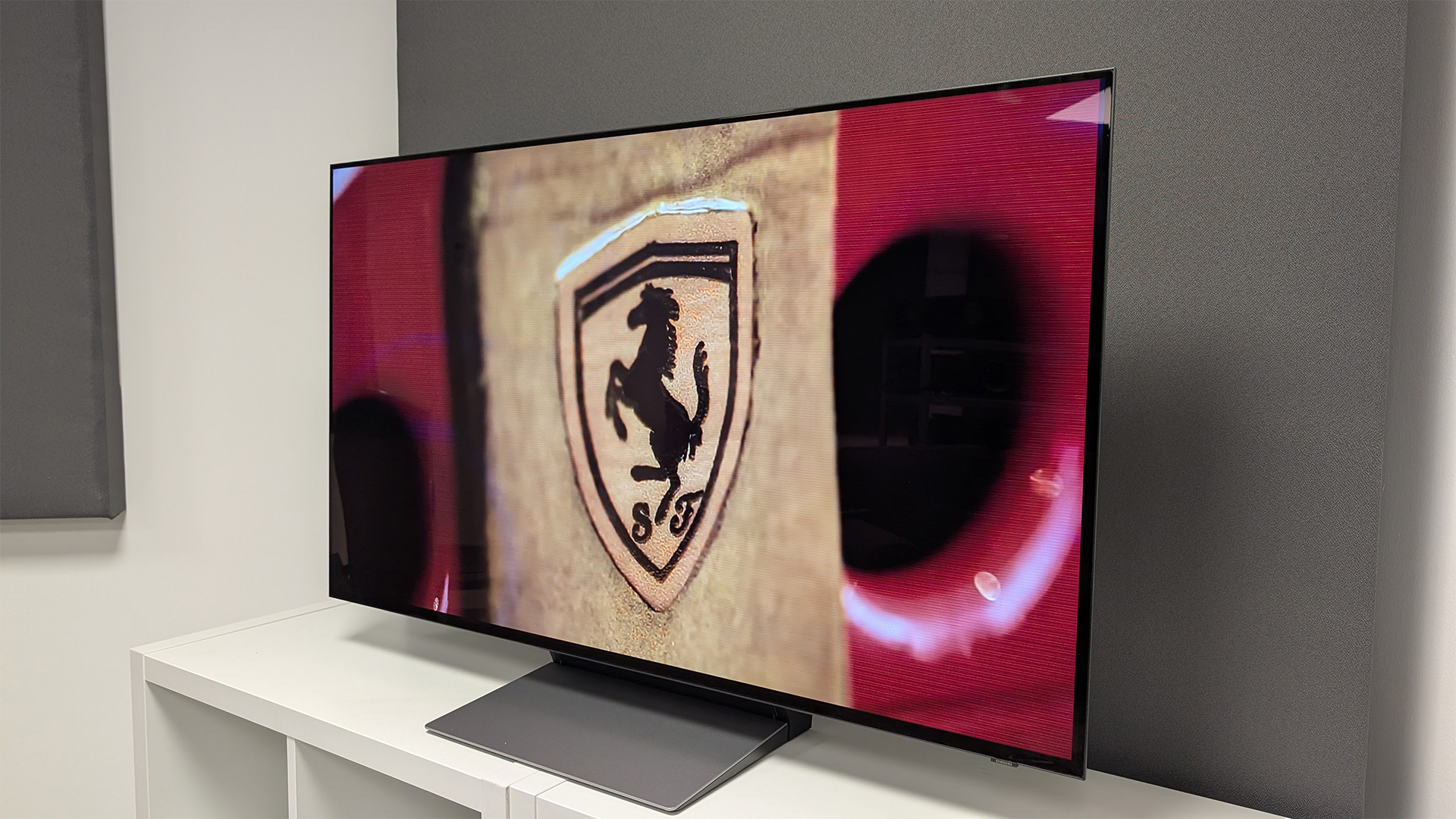 Samsung S90F 48-inch OLED TV slight side angle, on screen is Ferrari logo