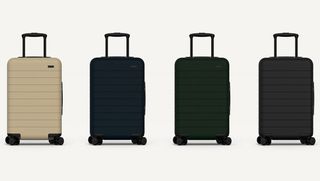 Four carry-on suitcases with eight spinner wheels. Colours: Beige, black, dark blue, dark grey.