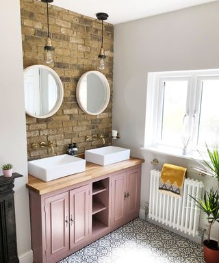 Bathroom with double basins and round wall mirrors, and exposed brick wall
