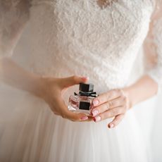 woman holding a bottle of fragrance on her wedding day