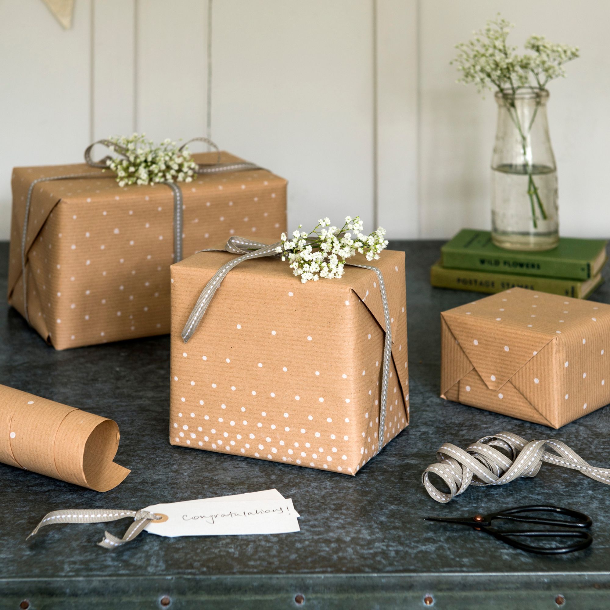 Collection of brown paper wrapped gifts. Polka dot wrapping, real flowers, handmade tags