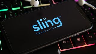 Sling TV logo on a smartphone against a lit up gaming keyboard