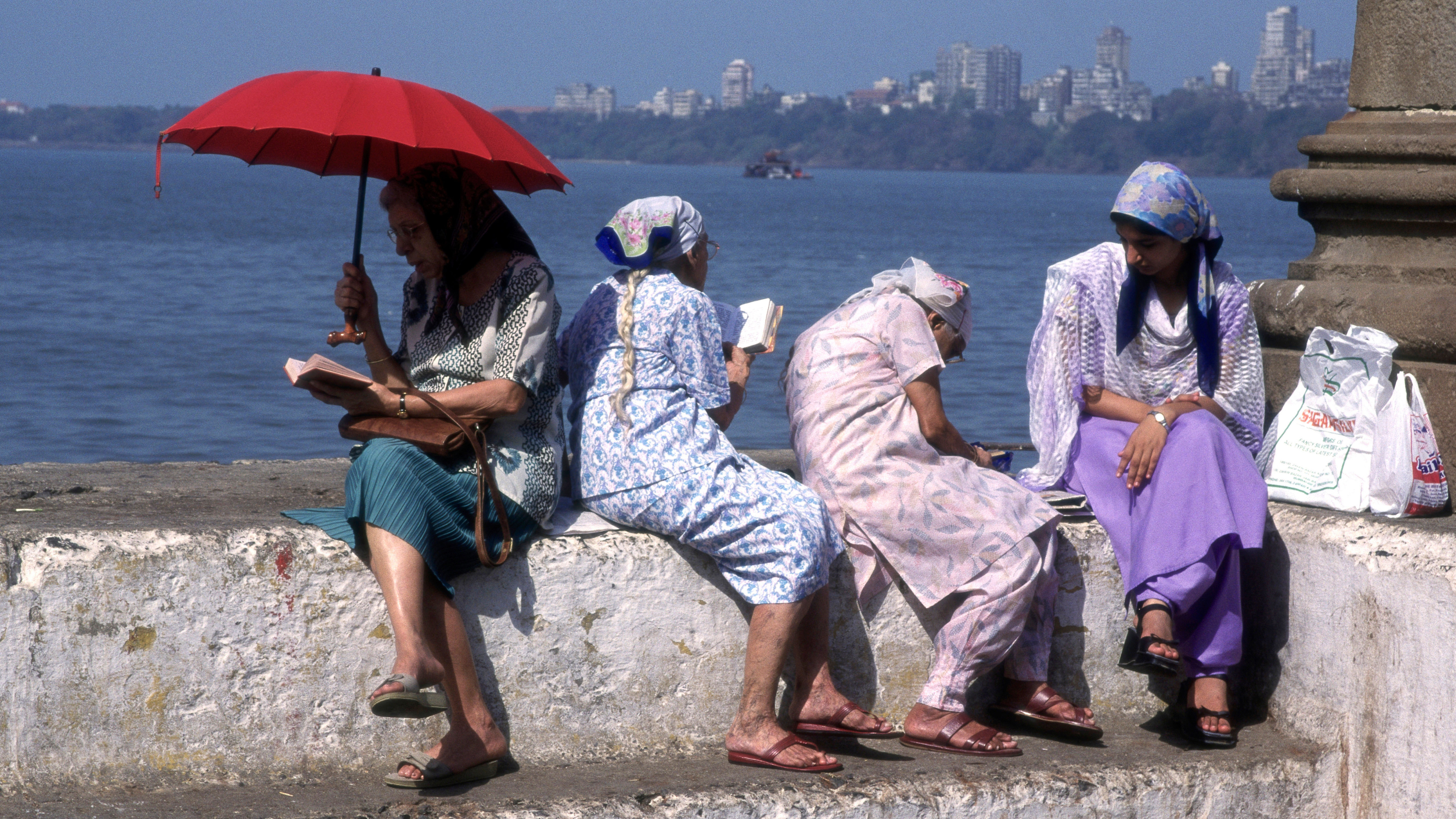 Quatro mulheres sentam-se à beira-mar e rezam