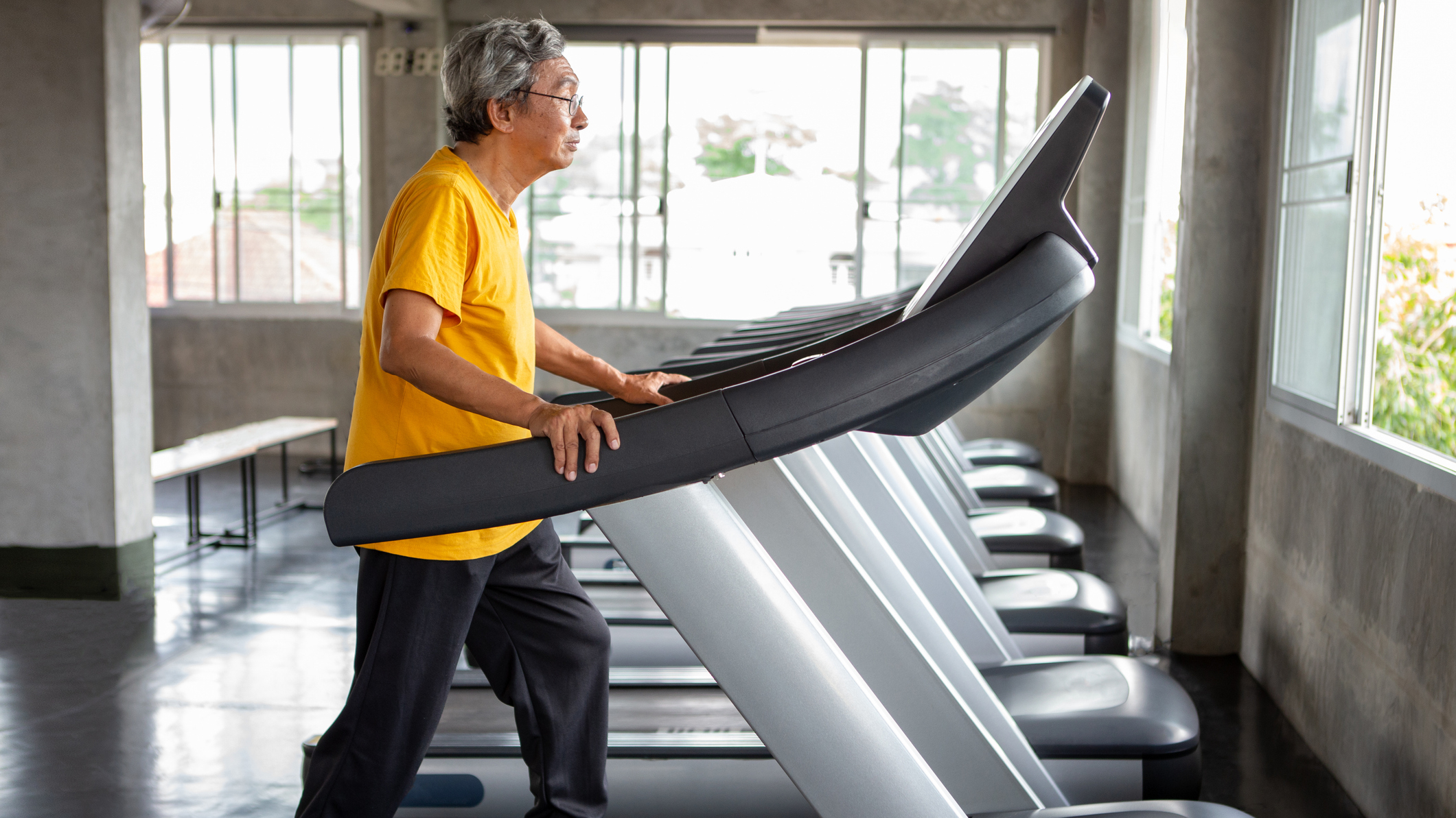 Senior man walking on treadmill in a gym
