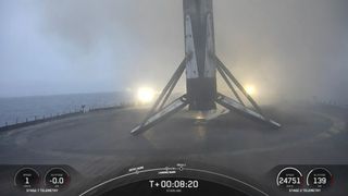 A black and white spacex falcon 9 rocket first stage sits on the deck of a ship at sea.