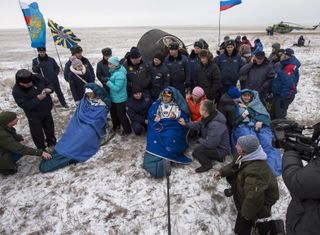 Alexander Gerst (left), Maxim Suraev and Reid Weisman are seen seated in front of their Soyuz TMA-13M spacecraft after landing on the snow-covered steppe of Kazakhstan, Nov. 9, 2014.