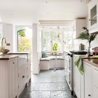 kitchen with white wall white cabinet white window and stone flooring