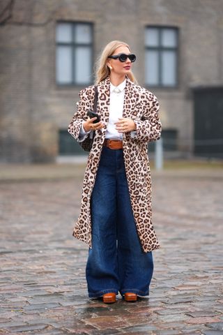 woman wearing leopard print coat, white button down, and wide-leg jeans