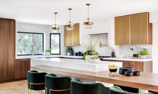 white kitchen with glass pendant lighting and wooden cabinets by Lindye Galloway