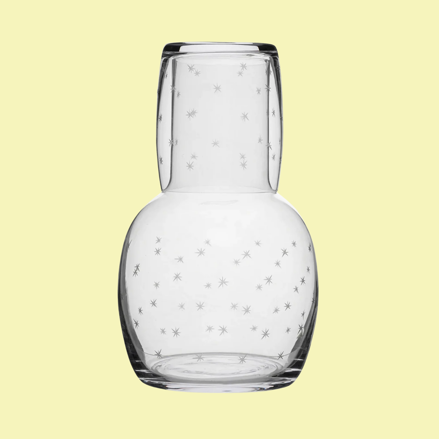 A glass carafe and cup with etched stars