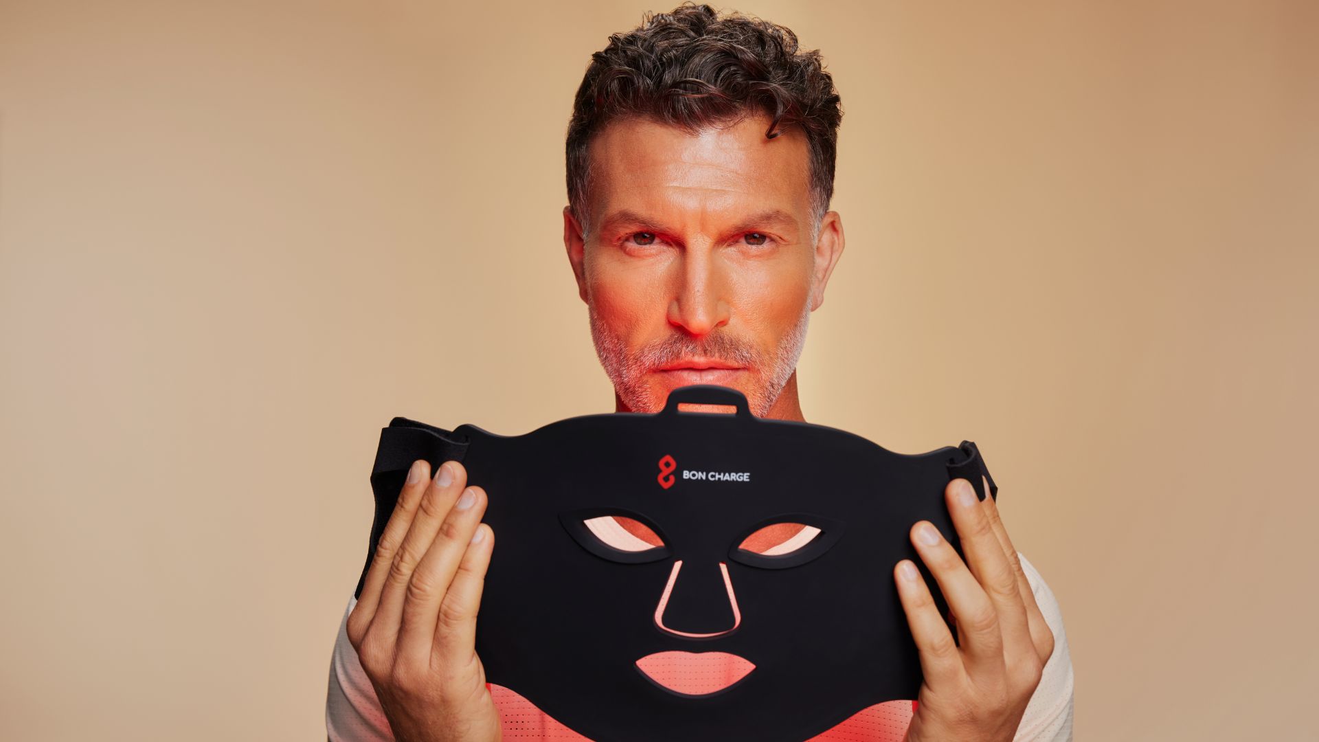 an image of a man holding the BON CHARGE red light face mask