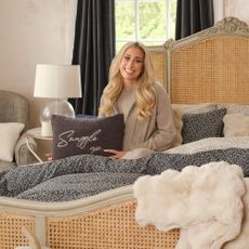 Stacey Solomon sitting on a rattan bed covered in her George Home ditsy floral bedding