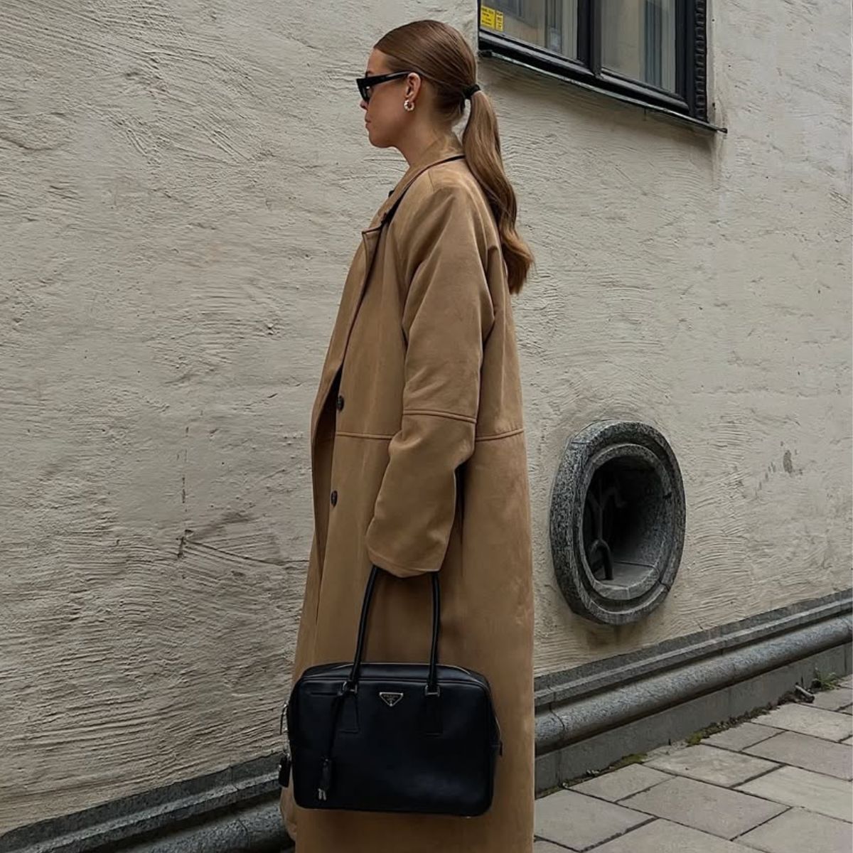 @haaannajohansson wears a camel coat, Prada bowling bag and sunglasses