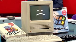BBC Breakfast footage featuring Apple Macintosh SE computer next to physical copies of MS DOS and Windows 95 with Microsoft keyboard in front.