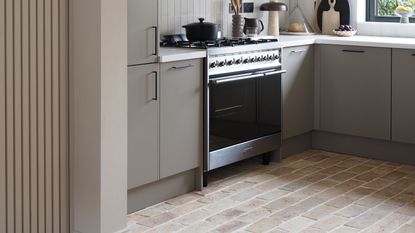 a neutral kitchen with brown kitchen cabinets and a brick floor