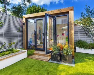 timber clad garden room in small urban garden with grey slatted fences