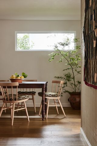 dining room with tall window, potted plant and timber table